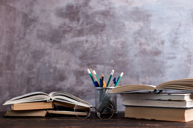 Bolígrafos, manzana, lápices, libros y vasos sobre la mesa