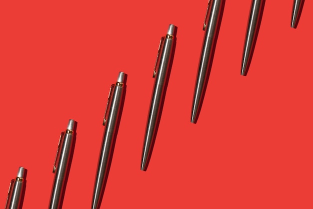 Foto bolígrafos de metal sobre un patrón de fondo rojo