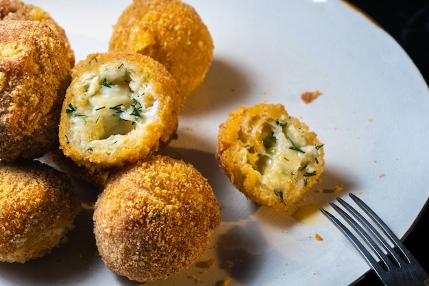 Bolinhas de queijo com endro dentro para um lanche em um prato em um fundo preto.