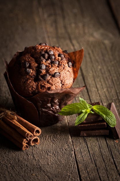 bolinho cozido escuro de chocolate com hortelã em uma mesa de madeira com canela, anis, chocolate.