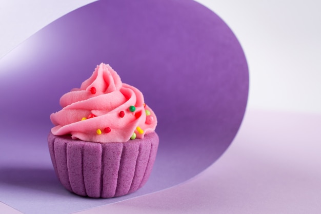 Bolinho de açúcar decorativo roxo na luz de fundo com granulado