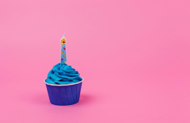 Bolinho de aniversário azul com uma vela em um fundo rosa Espaço para texto