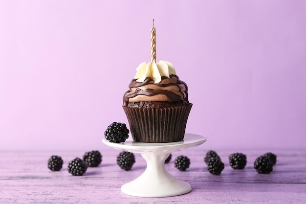 Bolinho de chocolate saboroso com frutas e vela no fundo roxo