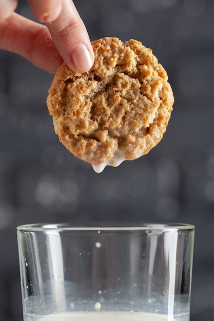 Bolinho de dunking de mão feminina em leite close-up