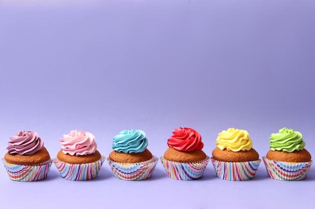 Bolinho delicioso com uma vela em um fundo colorido com espaço para texto