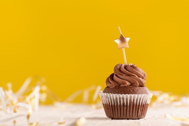 Bolinho festivo em fundo amarelo. Bolinho de chocolate com velas em forma de estrela. Copie o espaço.