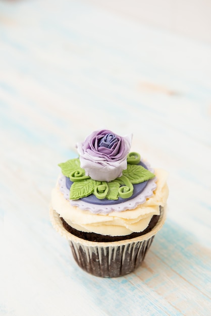 Bolinho roxo único com uma flor em madeira