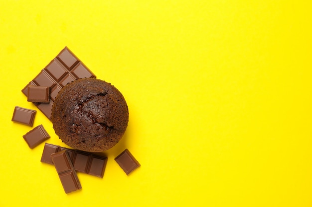 Bolinho saboroso e chocolate em fundo amarelo, vista superior