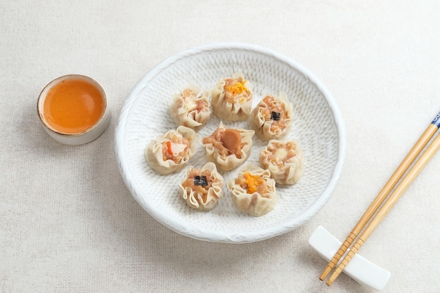 Bolinhos chineses Mini Dim Sum servidos em prato branco com molho e pauzinho Fechar