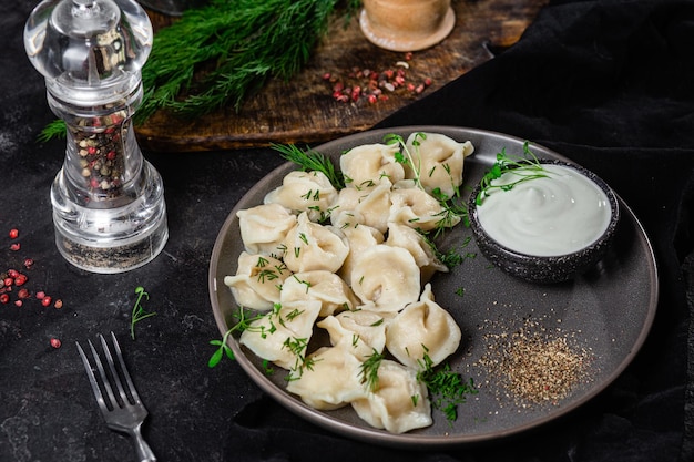 Bolinhos com creme azedo e ervas em um prato escuro Bolinhos de carne