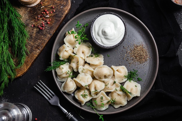 Bolinhos com creme azedo e ervas em um prato escuro Bolinhos de carne