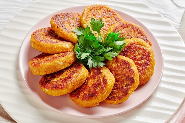 Bolinhos de abóbora com curry vegan em um prato branco com salsa servidos em uma superfície de madeira branca, vista de cima, close-up