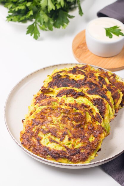 Bolinhos de abobrinha vegetarianos ou panquecas de abobrinha, servidos com ervas frescas e creme de leite.