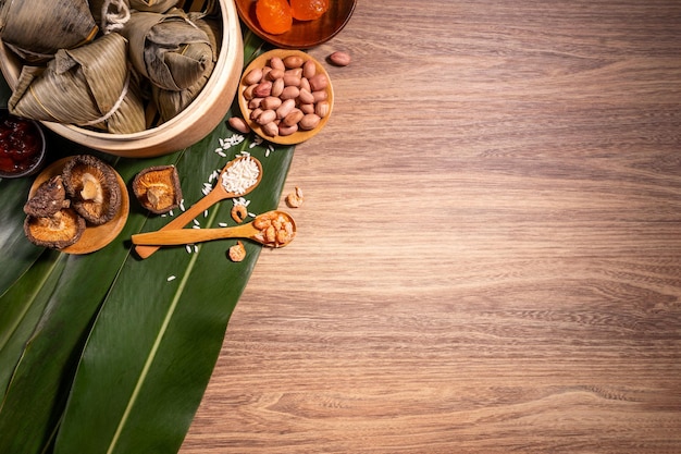 Bolinhos de arroz cozido no vapor Zongzi na mesa de madeira bambu deixa comida no conceito de duanwu do festival do barco dragão fechar espaço de cópia vista de cima