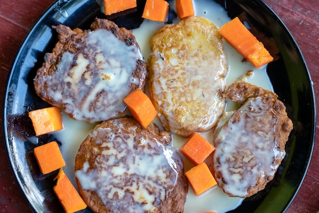 Bolinhos de banana com leite condensado e mamão em chapa preta no café da manhã Deliciosa sobremesa closeup