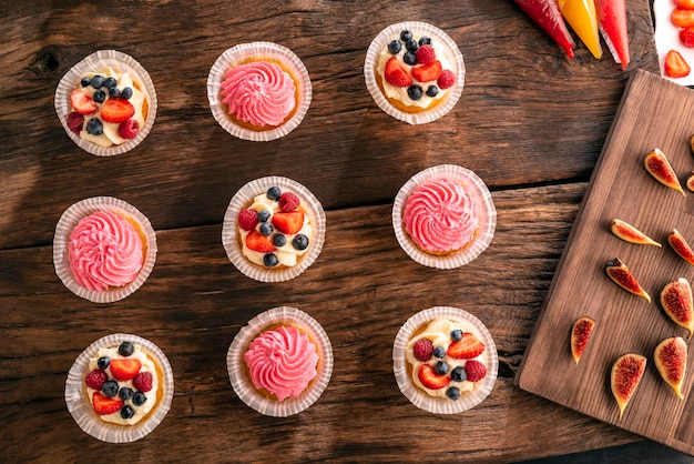 Bolinhos de baunilha planos com frutas frescas e figos na mesa de madeira escura Vista superior Pastelaria doce Confeitaria