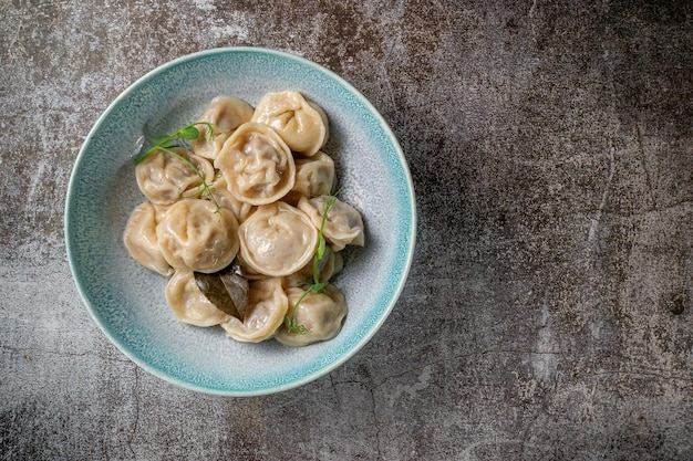 Bolinhos de carne com especiarias em um prato com verduras no fundo de uma mesa de pedra cinza