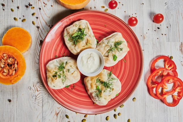 Bolinhos de carne ravióli de pelmeni russo com carne em um prato branco sobre uma tábua de madeira