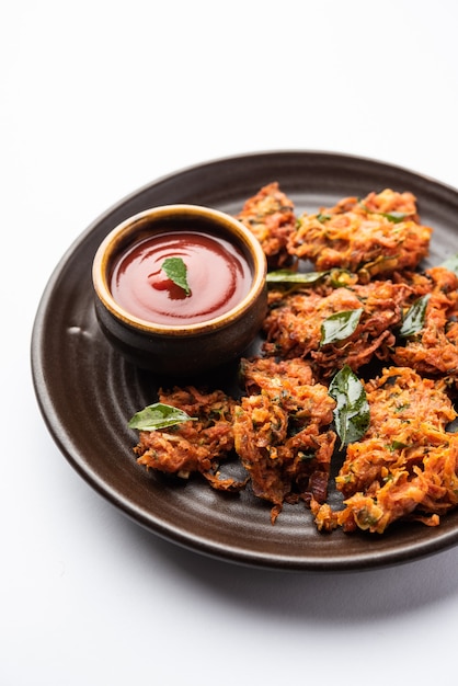 Bolinhos de cenoura ou Gajar ke pakore ou pakode ou bajji ou bhaji, lanche indiano servido em um prato com ketchup de tomate