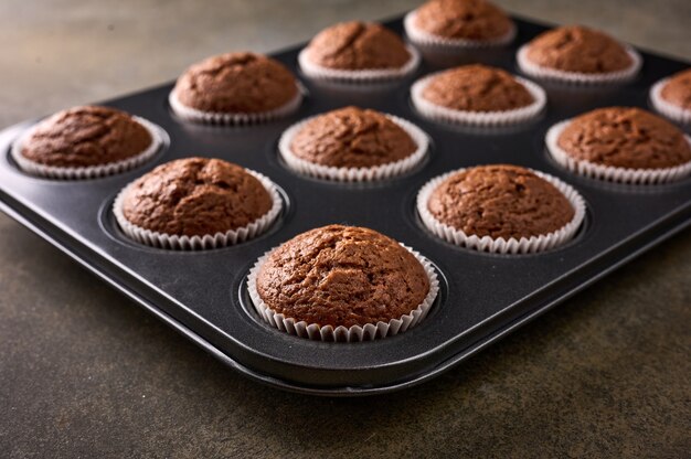 Bolinhos de chocolate caseiros em forma de cozimento numa superfície de madeira, foco seletivo, close-up