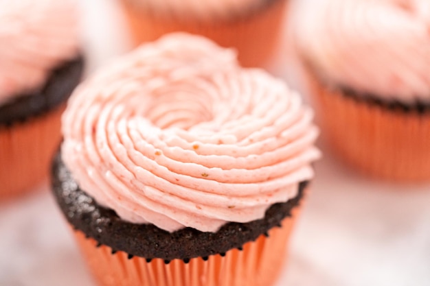 Bolinhos de chocolate com cobertura de creme de manteiga de morango.