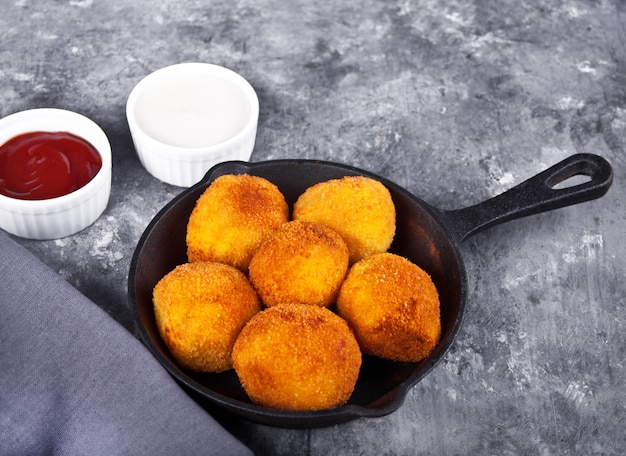 Bolinhos de croquetes de batata na frigideira de ferro e molhos de molhos.