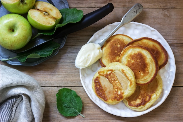 Bolinhos de maçã caseiros com creme de leite, café e maçãs verdes em uma madeira