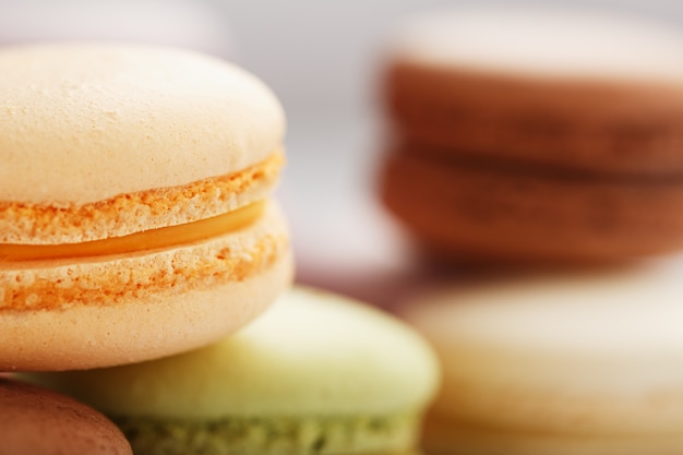 Bolinhos de macarrão francês de cores diferentes estão sobre a mesa cinza. Ainda vida de confeitaria.