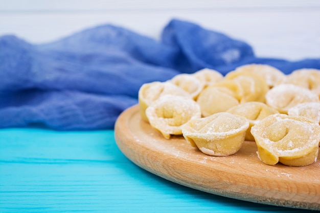 Bolinhos de massa crus caseiros, pelmeni, em de madeira.