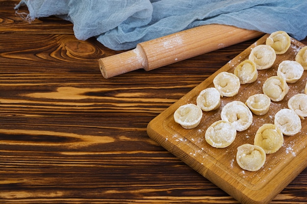 Bolinhos de massa crus caseiros, pelmeni, em de madeira.