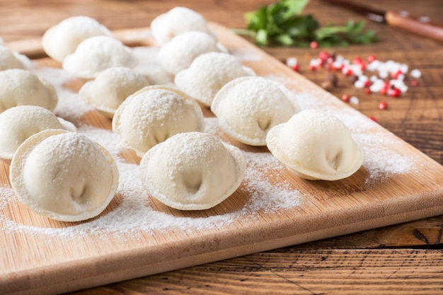 Bolinhos de massa crus em uma tábua de madeira na cozinha