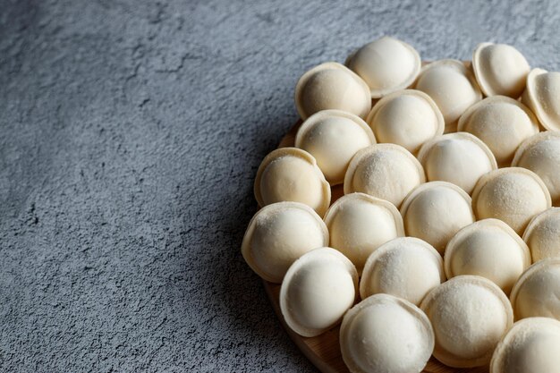 Bolinhos de massa crus estão em uma fileira em um fundo cinza