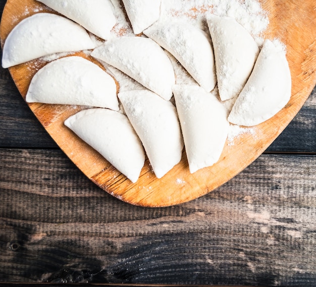 Bolinhos de massa crus polvilhados com farinha em uma placa de cozinha