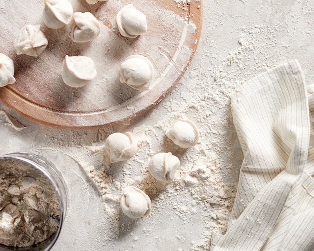 Bolinhos de massa russos crus com farinha na mesa