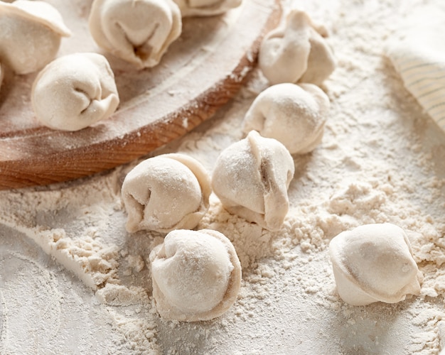 Bolinhos de massa russos crus com farinha na mesa