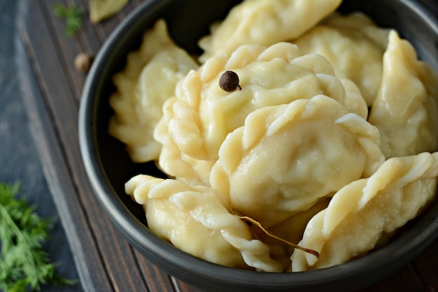 Bolinhos de massa vareniki pierogi pyrohy com batatas ervas especiarias e manteiga em uma tigela de cerâmica