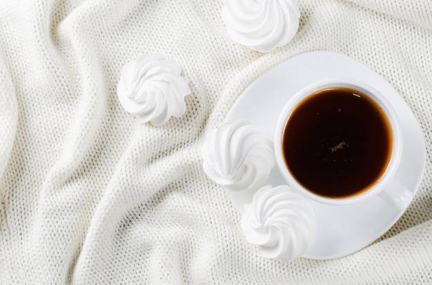 Bolinhos deliciosos da merengue e copo do chá quente.