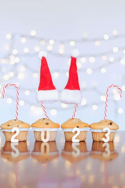 Bolinhos doces de natal e velas acesas em forma de números 2023. fundo branco com boque