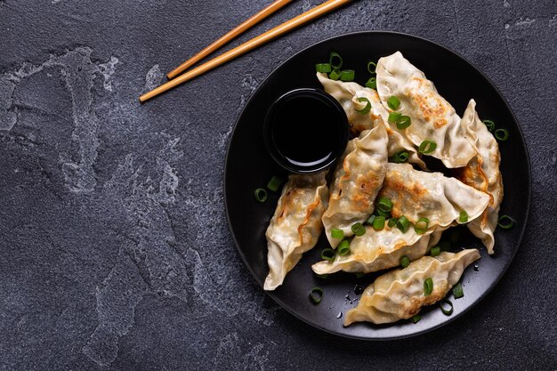 Bolinhos fritos Gyoza em um prato sobre um fundo cinza de concreto