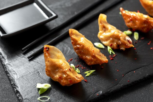 Bolinhos fritos japoneses com cebolas em um fundo preto gyoza é um prato muito popular no japão