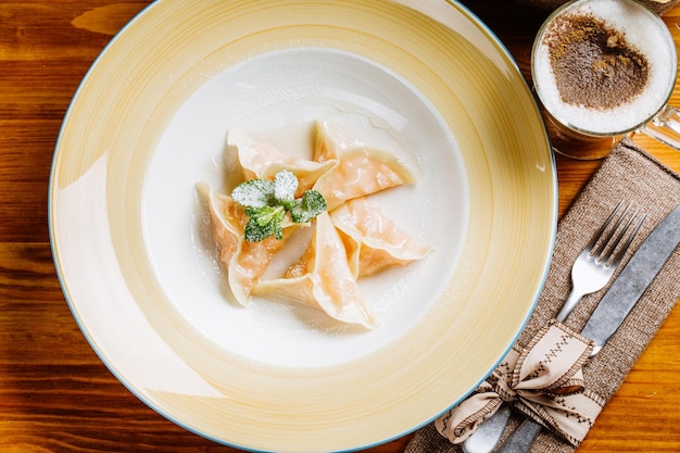 Bolinhos russos caseiros preparados cozidos ou pelmeni com abóbora no prato com conceito culinário e alimentar de hortelã fresca