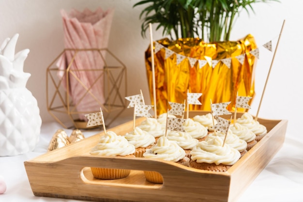 Bolinhos saborosos com creme na bandeja de madeira na mesa de férias com bandeiras