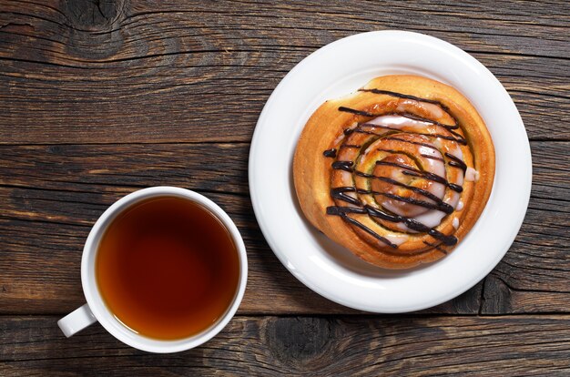 Bollo dulce con chocolate y taza de té en madera vieja