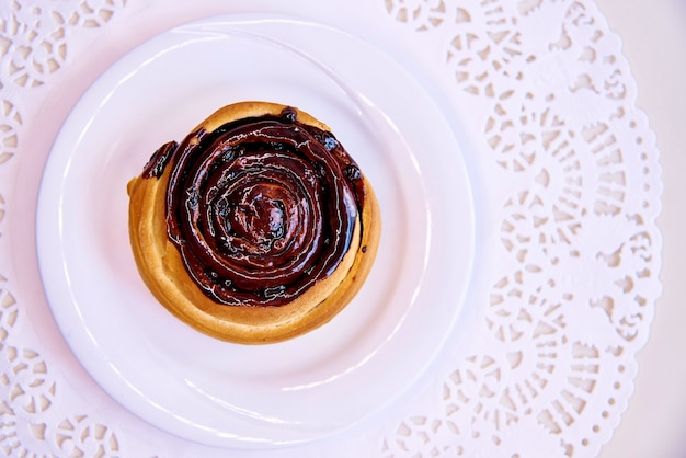 Bollo dulce con glaseado en un plato blanco con encaje.