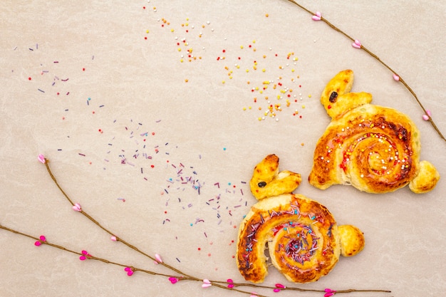 Bollo fresco en forma de un conejito de Pascua. El concepto de panadería de vacaciones para niños. En la superficie de piedra con ramas de sauce artificial, copie el espacio, vista desde arriba.