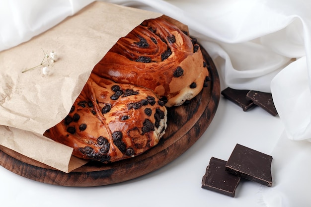 Bollo de mantequilla con gotas de chocolate en una bolsa de embalaje de papel sobre una mesa de luz