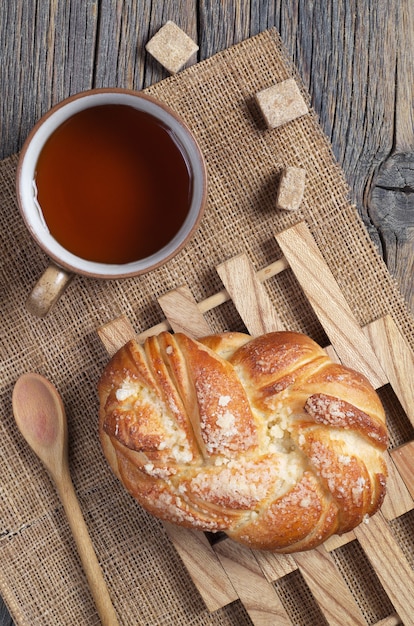 Bollo de mimbre dulce y taza de té sobre la mesa