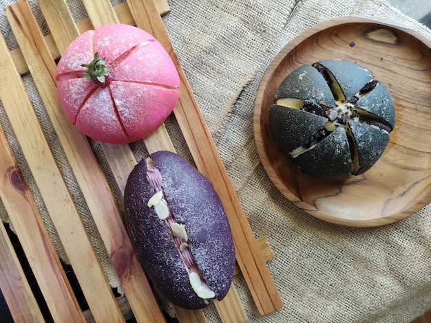 Un bollo morado con una parte superior roja se asienta sobre un plato de madera.