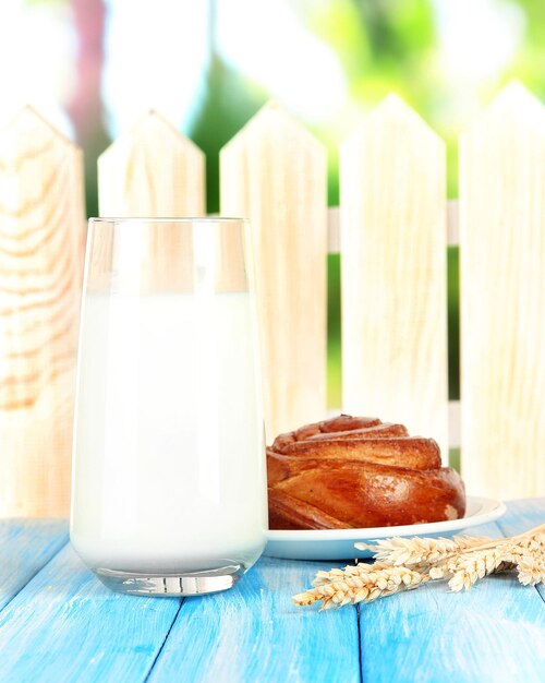 Foto bollo de pan y vaso de leche sobre fondo de madera azul