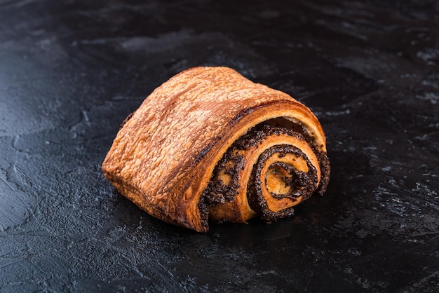 Bollo sabroso recién horneado en una mesa oscura Deliciosos productos horneados directamente de la panadería Fondo negro